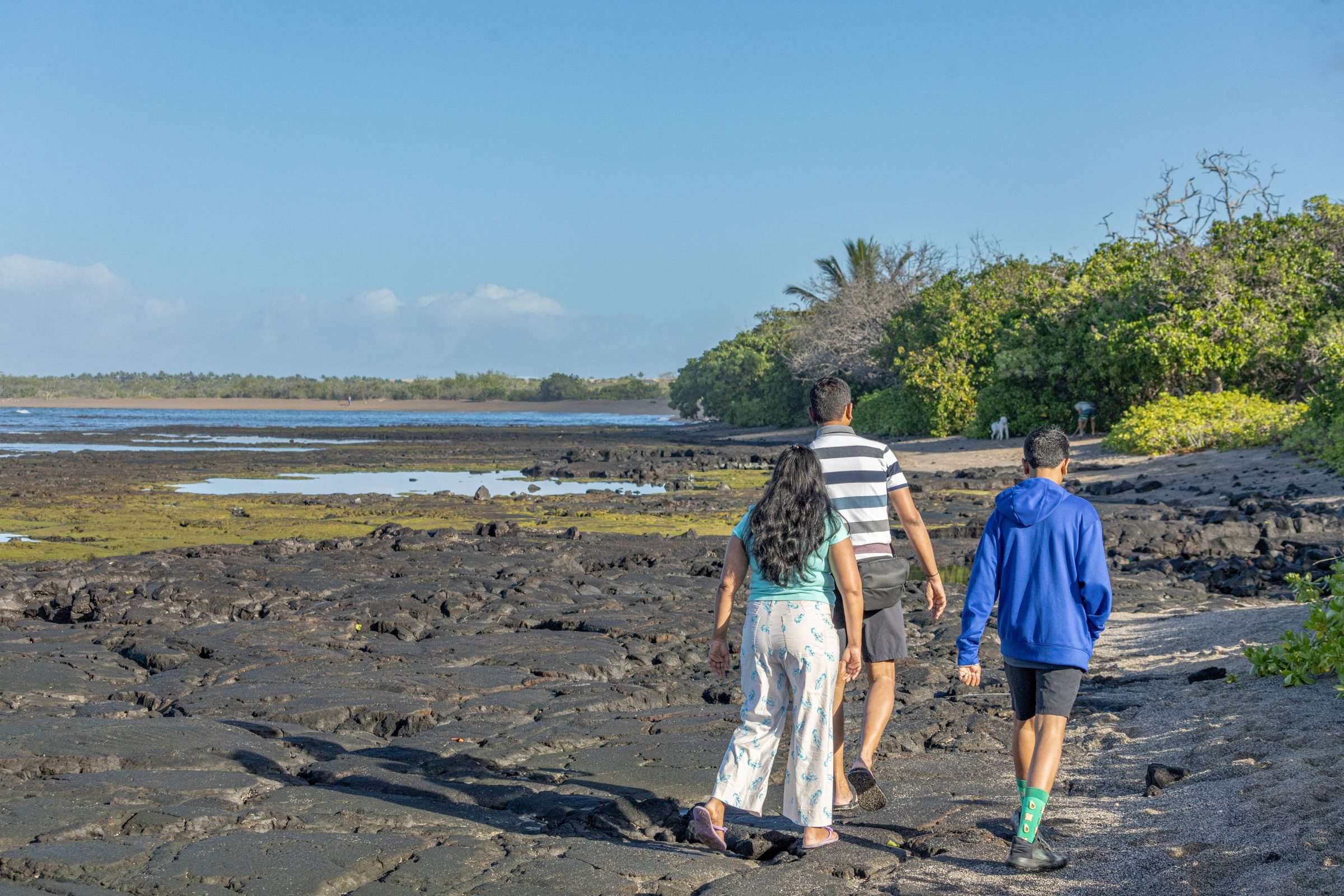 Guests walking along shoreline at Kaloko-Honokohau National Historical Park on a tour in Kona Hawaii.