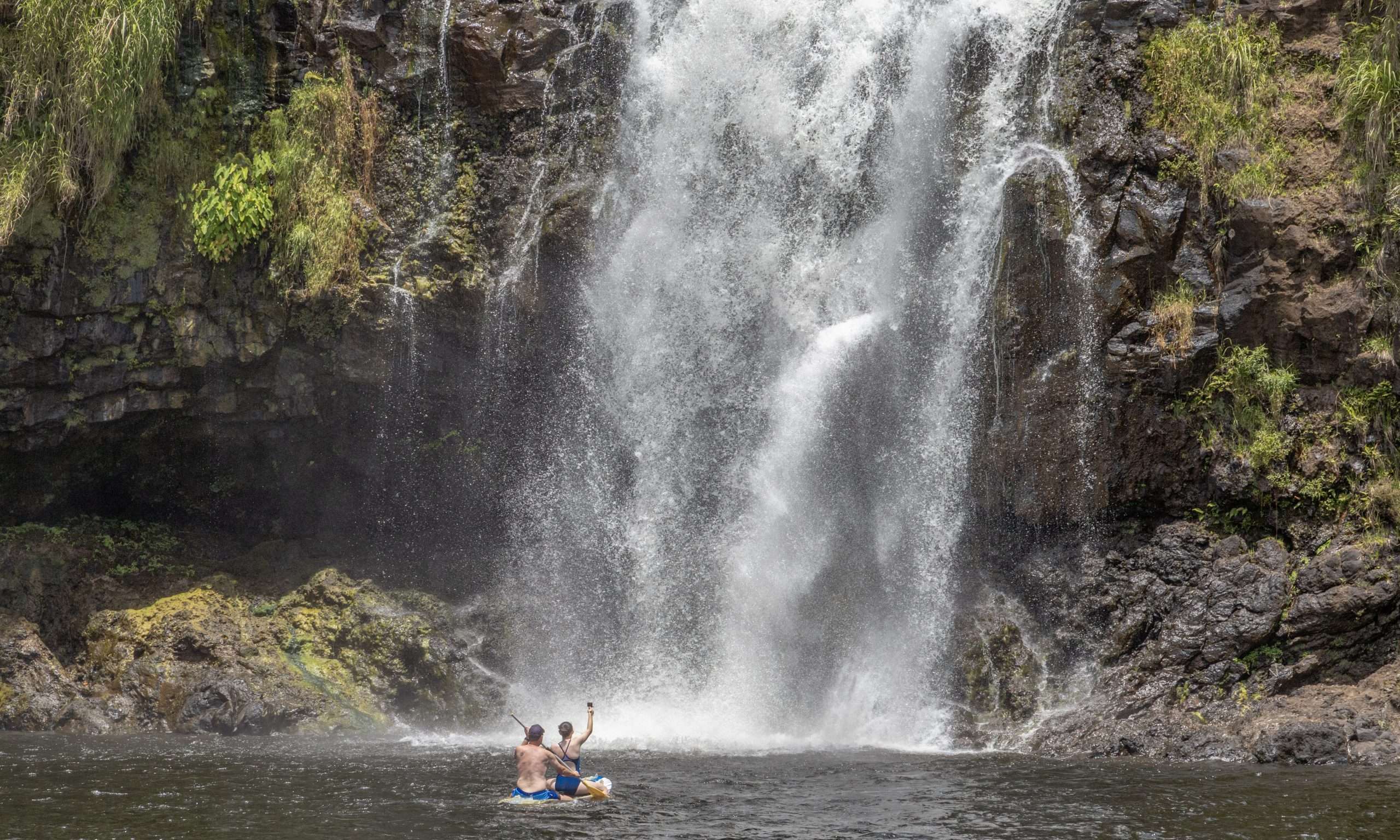 Hilo waterfall tour guests paddling at a private waterfall.
