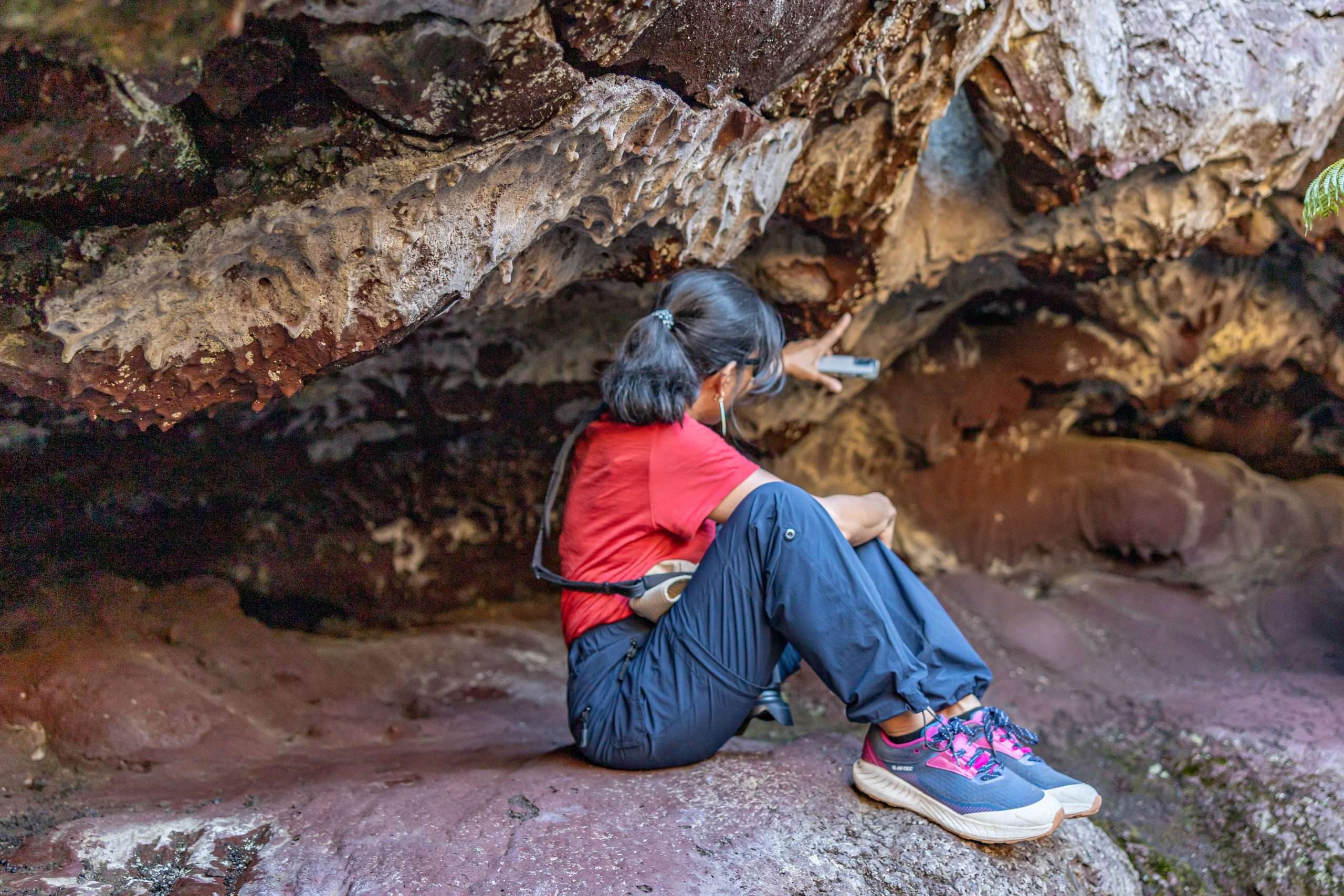 Woman sitting in a lava cave in Hawaii Volcanoes National Park.