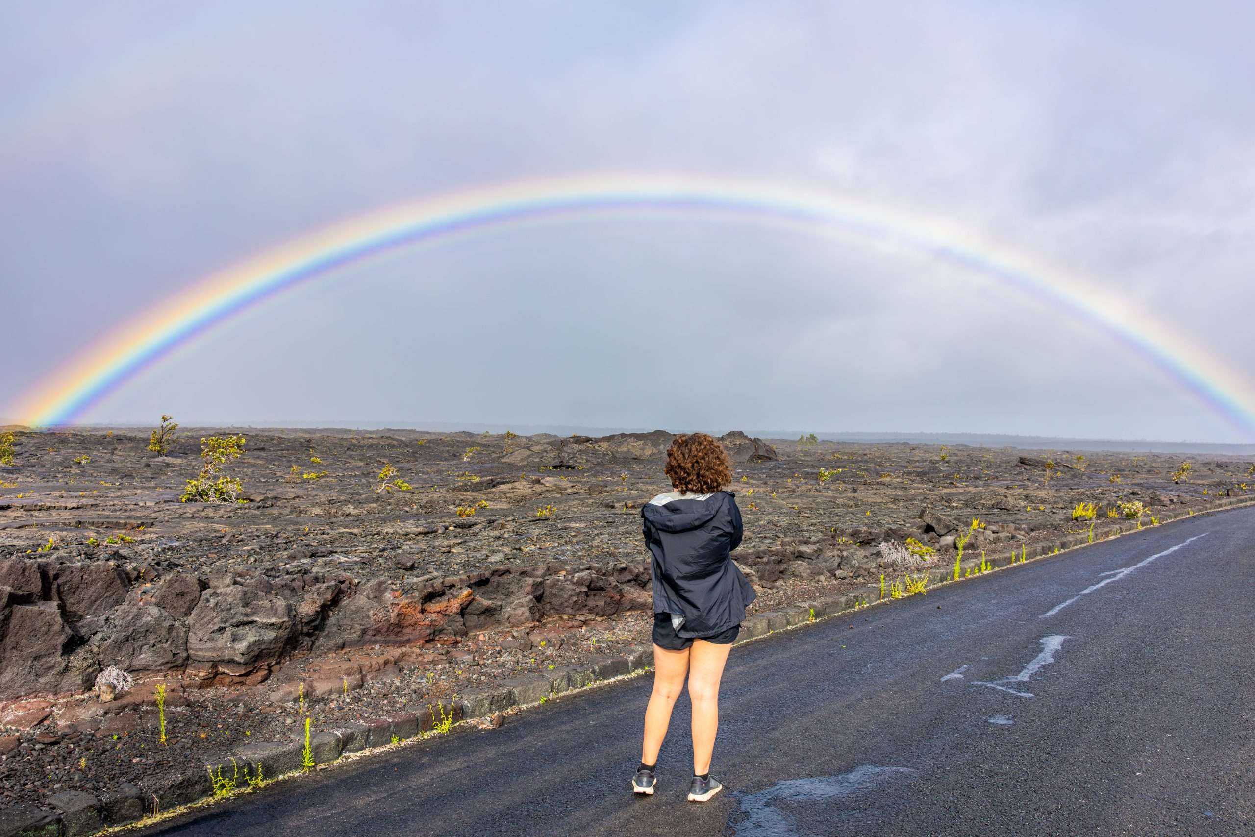 Big Island circle tour guest taking a photo of a rainbow at Hawaii Volcanoes National Park.