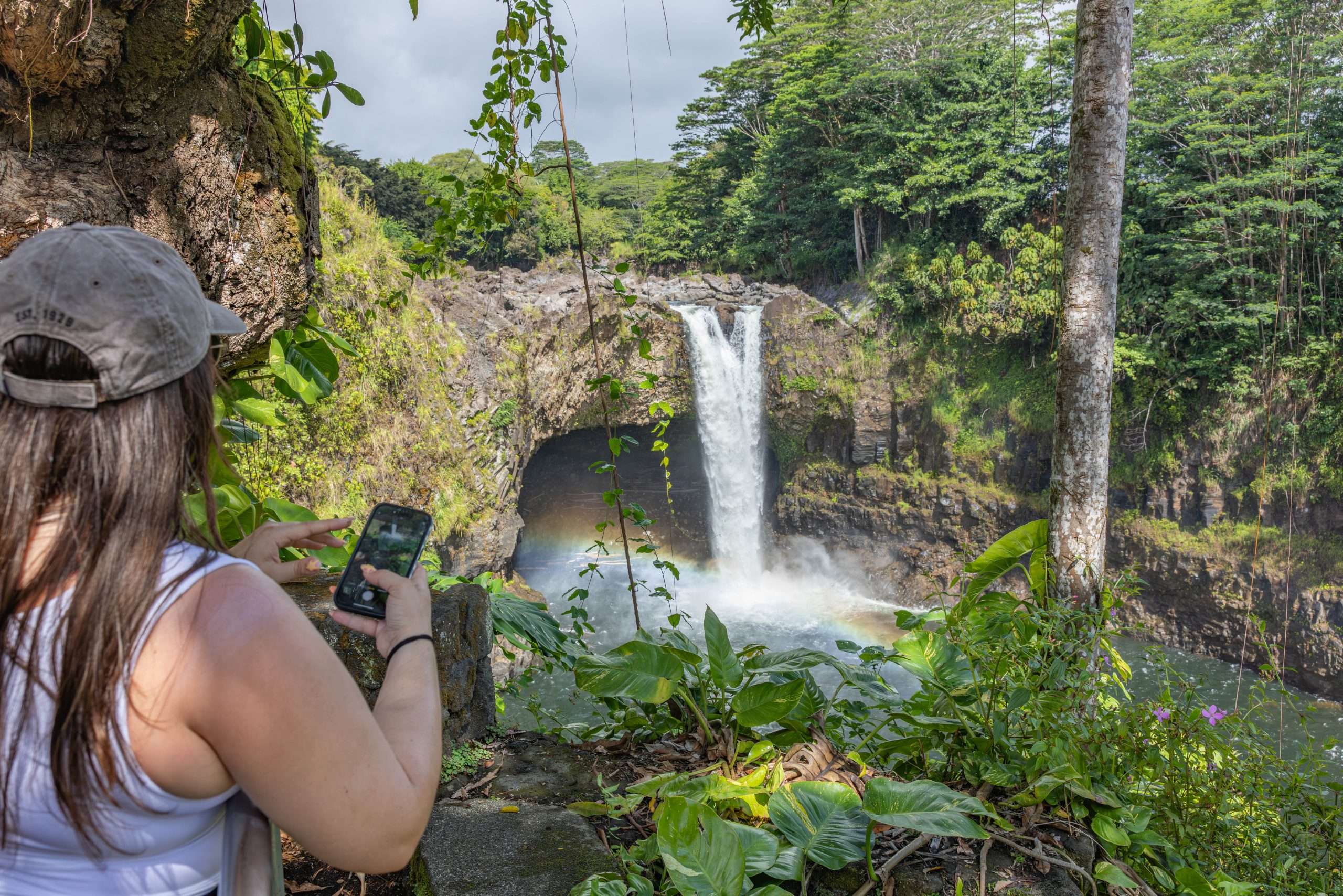 A guest taking a photo at Rainbow Falls on a Hilo shore excursion waterfall tour.