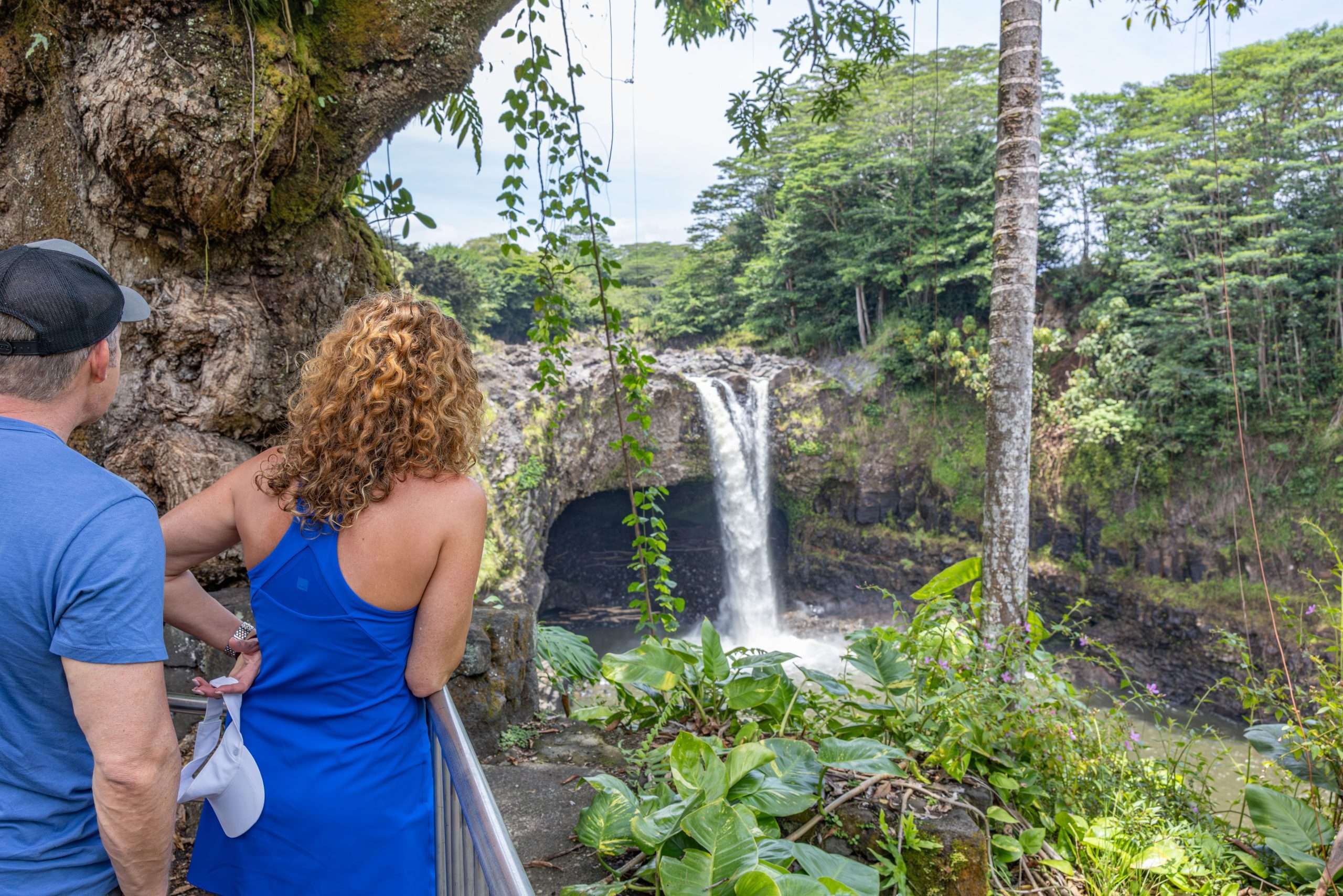 Big Island waterfall tour guests looking at Rainbow Falls while hearing guided interpretation of the legend of the falls.