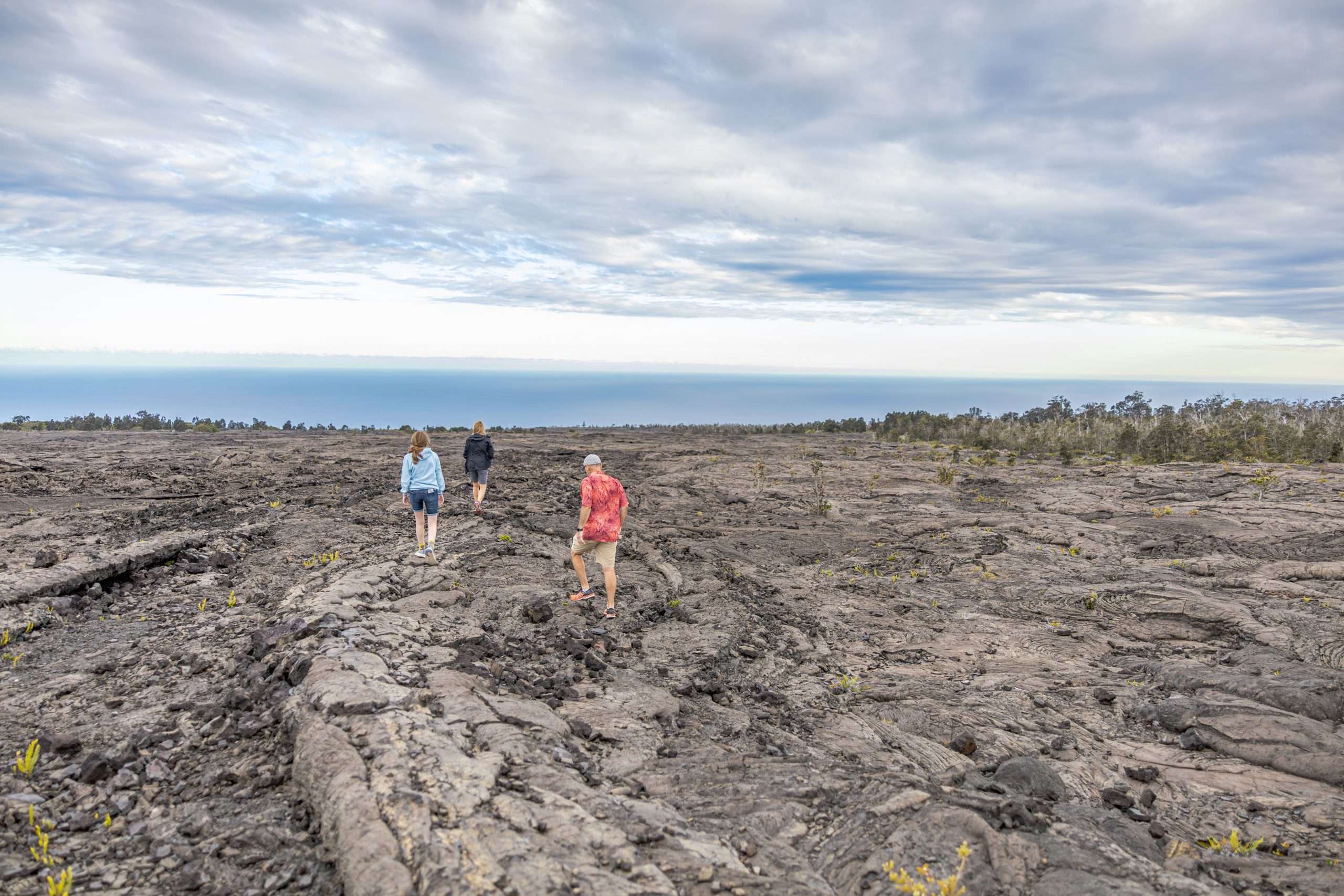 Kona Volcano Tours Kona volcano tours guest walking on old lava field in Hawaii Volcanoes National Park.